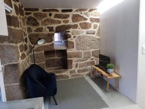 Habitación con pared de piedra, lámpara y silla. en Casa do Doutor Palheiro, en Travassos