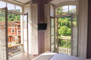 a bedroom with a bed and two large windows at La Venta de Miyares - Casa de Indianos in Piloña