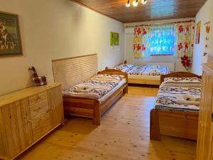 two beds in a room with wooden floors and a window at Ubytovanie v súkromí - Chata Zejmarka in Mlynky 