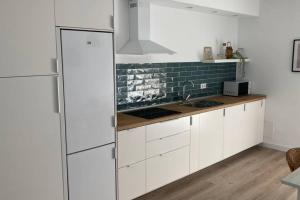 Una cocina con gabinetes blancos y un refrigerador. en Piso nuevo, céntrico y tranquilo, en Bullas
