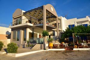 a large white building with a balcony with tables at Gonis Grand Luxury Suite in Palaiochora