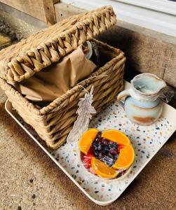 a basket with a plate of fruit and a pitcher at Kwetu Cabin in Bordon