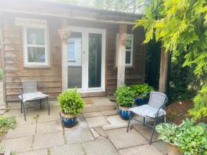 two chairs sitting on a patio in front of a house at Kwetu Cabin in Bordon
