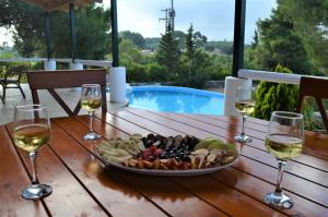 a tray of food on a wooden table with wine glasses at Elatia Villa in Volímai