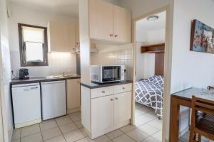 a small kitchen with a microwave and a bed at Résidence Lou Cout - à 200m de l'Océan in Vieux-Boucau-les-Bains