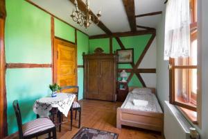 ein Wohnzimmer mit grünen Wänden und einem Tisch mit Stühlen in der Unterkunft Zagroda Chłopska in Gosław