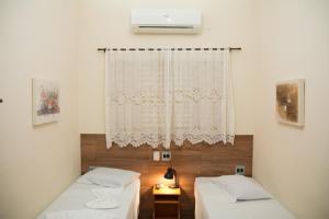 a room with two beds and a window with a curtain at Hotel Casa Grande in Orlândia