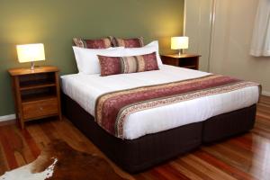 a bedroom with a large bed with two lamps at Yabbaloumba Retreat in Booloumba