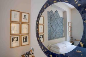 - un miroir dans une chambre avec un lit et des photos encadrées dans l'établissement Atelier Inès Arts & Suites, à Naples