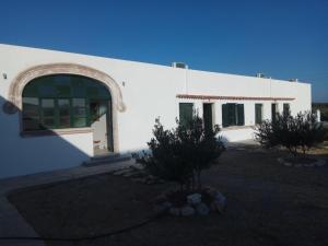 a white building with an arch doorway and trees at San Marco Guesthouse in Kattavía