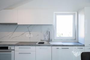 una cucina bianca con lavandino e finestra di Apartmani Vrtodusic a Rab
