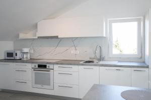 uma cozinha branca com um lavatório e uma janela em Apartmani Vrtodusic em Rab