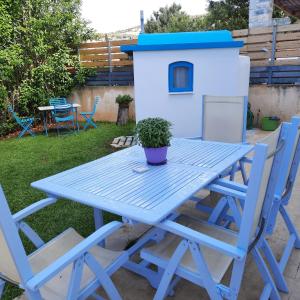 a blue picnic table with two chairs and a house at CHRYSTALL'S COTTAGE in Lagonissi