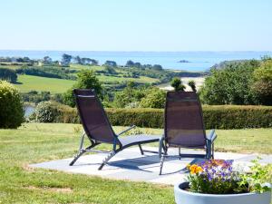 deux chaises assises sur une dalle en béton avec des fleurs dans l'établissement La Douce Escapade - Crozon, à Crozon