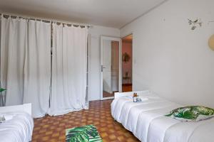 een kamer met 2 bedden met witte lakens en een raam bij Appartement Cyria - Welkeys in Saint-Cyr-sur-Mer