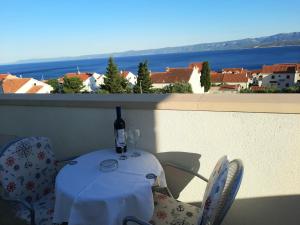 a table with a bottle of wine sitting on a balcony at Studio Apartments Regina in Bol