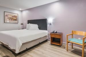 a bedroom with a bed and a table and a chair at Knights Inn North Richland Hills in North Richland Hills