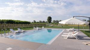 a swimming pool with chairs and a white umbrella at Country House Campofiore in Pontelongo