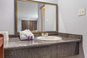 um balcão de casa de banho com um lavatório e um espelho em Knights Inn North Richland Hills em North Richland Hills