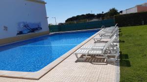eine Reihe von Stühlen neben einem Pool in der Unterkunft Falésia Beach Villa in Olhos de Água