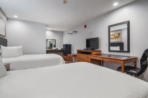 um quarto de hotel com duas camas e uma televisão em Knights Inn North Richland Hills em North Richland Hills