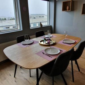 a wooden table with chairs and plates and wine glasses at Luxury Loft Apartment Akureyri in Akureyri