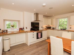 a kitchen with white cabinets and a wooden table at Hetland in Dumfries