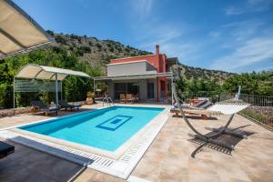 a swimming pool with chairs and a house at Dalasvillas SkalaMare in Skala