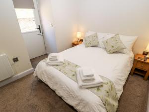 a bedroom with a white bed with towels on it at 1 Barn Cottages in Halifax