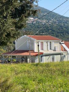 une maison blanche avec un toit rouge dans un champ dans l'établissement Julia house, à Pilaroú