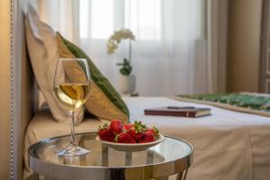 a table topped with a glass of wine and a plate of fruit at Boutique Hotel del Corso in Florence