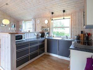 a kitchen with blue cabinets and a microwave at Holiday home Sæby II in Sæby