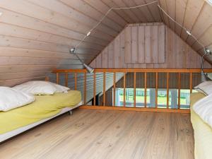 two beds in a room with wooden walls and wood floors at 6 person holiday home in Harbo re in Harboør
