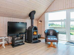 a living room with a fireplace and a tv and a chair at 6 person holiday home in Harbo re in Harboør