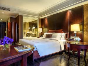 a bedroom with a large bed and a table and a desk at Hotel Muse Bangkok Langsuan - MGallery in Bangkok