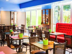 un restaurante con mesas, sillas y ventanas en Ibis Styles Porto Alegre Centro, en Porto Alegre