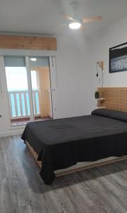 a bedroom with a black bed in a room with a window at Apartamento Dos mares I in La Manga del Mar Menor