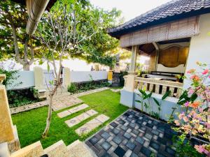 a garden with a house and a yard with a lawn at Solaluna Beach Homestay in Amed