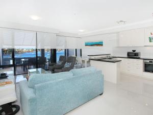 a living room with two blue couches and a kitchen at Kirribilli 13 in Mooloolaba