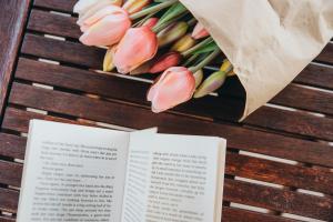 a book and a bouquet of pink tulips at Anatota Hvar in Hvar