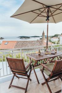 a table and chairs with an umbrella on a balcony at Anatota Hvar in Hvar