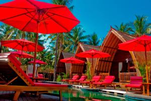 a pool with red chairs and red umbrellas at D'Wahana Resort in Gili Trawangan