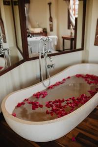 a bath tub filled with red flowers in a bathroom at Paua Hotel Boutique in Pipa