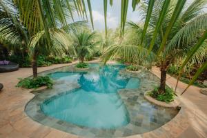 a swimming pool with palm trees in a resort at Paua Hotel Boutique in Pipa