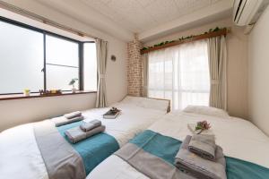 two twin beds in a room with a window at nestay suite tokyo tabata in Tokyo