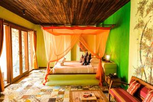 a bedroom with a bed in a room with green walls at Bali Bohemia Huts in Ubud