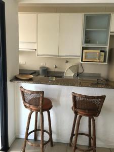 una cocina con 2 taburetes y una barra en Guarujá Pitangueiras Flat Capitania Varam, en Guarujá