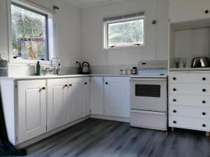 a white kitchen with white cabinets and a sink at Cozy guesthouse at the Rabbithole, Akatarawa Valley in Upper Hutt