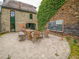 un patio con tavolo e sedie di fronte a un edificio in mattoni di Beautiful home in L glise with a garden and pond a Léglise