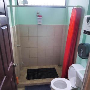 a bathroom with a toilet, sink, and shower stall at Kalunai Hostel in Puerto Viejo